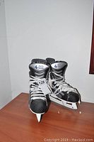 Front view of the pair of CCM Prolite 3 men's ice hockey skates size 10 showing the black and silver color scheme and white laces.