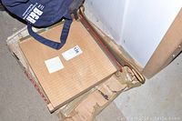 Front-angle photo showing the wooden base with grid markings, metal cutting arm with brass handle, and part of a blue bag.