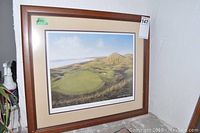 Overall view of the framed print showing landscape of golf course and surrounding area.