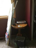 Photo of side table, ironing board, puzzle, iron and file box in corner by window