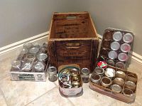 Wooden crate with multiple mason jars and lids arranged around it on tiled floor.