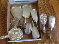 Top view of box containing four silver hand mirrors and two hair brushes