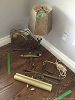 View of small table lamp with gilt shade, artwork lights and brass gong on wood floor
