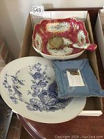 Wide view of small blue dish, large blue and white plate, red and white bowl with ladle