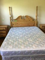 Full view of queen size bed with mattress and solid wood headboard, showing scratches and wear on wood.