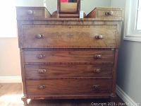 Straight on view of full antique mahogany dresser showing drawer handles and wood grain finish