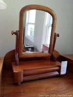 Front view of antique wooden vanity mirror showing tilting mirror with rounded top corners and drawer base