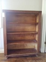Front view of the Crug vintage Canadian wood bookcase showing 3 fixed shelves and visible wear on surfaces