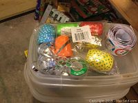 Photo showing a Rubbermaid container lid with colorful polka-dot Christmas crackers, silver ribbons, small packages, and a roll of Christmas-themed paper.