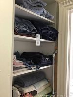 Shelves with neatly folded towels in multiple colors including gray, navy blue, light pink and beige.