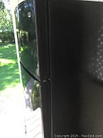 Side view of black Maytag refrigerator showing scratches on the side panel.
