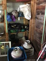 Photo showing propane tanks on floor in front of metal shelving with camping gear above and around