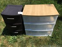 Photo of two storage containers placed on grass; brown plastic container with three drawers to the left and clear drawer organizer with wooden top to the right.