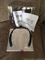 Headband seated in original plastic tray alongside two paper booklets