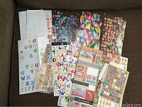 Photo showing an assortment of scrapbooking stickers including alphabet and decorative types, word and phrase stickers, and embellishment stickers.