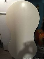 Top-down view of kidney-shaped white table top showing shape and surface wear