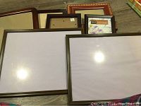 Overview of the various picture frames laid out, showing different sizes and finishes including wood and metal frames with glass fronts.