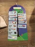 Wooden daily organization chart with 12 task magnets arranged on it, hung vertically on wall