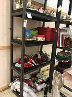 Shelf display showing grouped holiday items including boxes, stockings, red storage container, decorative berries and pine cones.