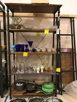 Front view of one shelving unit loaded with vases, glassware, and cookware showing metal frame and wood shelves