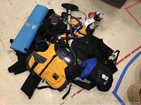 Photo of the entire lot showing three life vests, wetsuits, bike pump, kayak carrier kit, chaps, tennis racket, flashlight and LED lantern on floor.