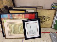Nine framed art prints stacked together showing the variety of frames and sizes