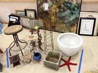 View of entire lot showing various outdoor planters, iron plant stands, a stool, and lantern with some framed art in background