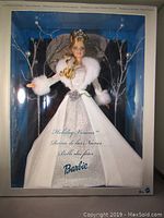Front view of boxed 2003 Holiday Visions Barbie doll wearing white and silver gown with fur trim and tiara, displayed in box with winter background and decorative branches