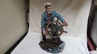 Front view of the sea captain figurine showing detailed face, blue coat, and ship's wheel.