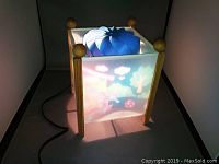 Front view of the dream lamp lit with colorful images and rotating interior visible.