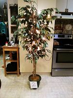 Full view of the artificial ficus tree standing about 5 feet tall with green leaves and black pot base.