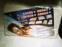 Front view of unopened neck protection pillow in plastic packaging with branding and product details in multiple languages.