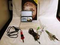 Overview of all items in lot: three woodburning tools with cords, book of patterns, and metal box of tips
