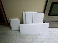Front view of all canvases stacked and displayed on floor showing sizes and condition.