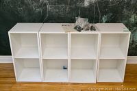 All four matching IKEA Eket shelving units side by side with assembly hardware and instructions on top.