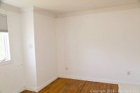 Empty room corner showing white baseboards along the floor and wall edges with wood floor visible.