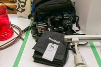 Nikon F90 camera with lens, flash, camera bag, and battery bag arranged together on table.