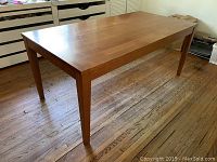 Three-quarter view of the rectangular wood dining table showing top surface and leg design