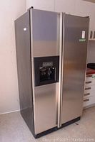 Full view of Kenmore stainless steel side-by-side refrigerator, showing water and ice dispenser on freezer door.