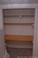Full view of the pine shelving unit showing three horizontal wooden shelves installed in a recess wall space.