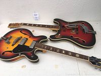 Two semi-hollow electric guitars laid side by side