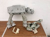 Gray AT-AT Walker and green Slave I ship on wood table, front view