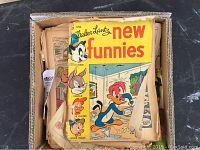 Box of loose old comics with a Walter Lantz New Funnies comic on top featuring cartoon characters including Oswald and Andy Panda.