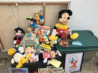 Full view of lot showing multiple Disney plush toys including Mickey Mouse, Minnie Mouse, Donald Duck, Disney castle playset, and a framed Sorcerer's Apprentice print.