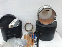 Full lot showing Yamaha marching snare drum on one case, second hard case, drumsticks, mallets, tambourine and other drum supplies.
