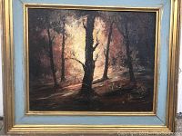 Full view of oil painting showing forest scene with trees and light filtering through, set in a light blue and gold wood frame.