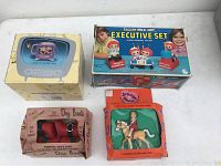 Three boxed vintage toys: Raggedy Ann & Andy Executive Set, Jennys Home doll on horseback, and red Dog Boot in boxes.
