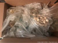 Top-down view of box filled with multiple resealable plastic bags containing assorted jewelry pieces.