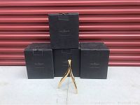 Four black Moet & Chandon branded boxes stacked with one gold-tone champagne chandelier standing in front of them.