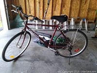 Side view of the maroon Raleigh Sprite men's bicycle showing 22 inch frame, tires, kickstand, and rear metal rack.
